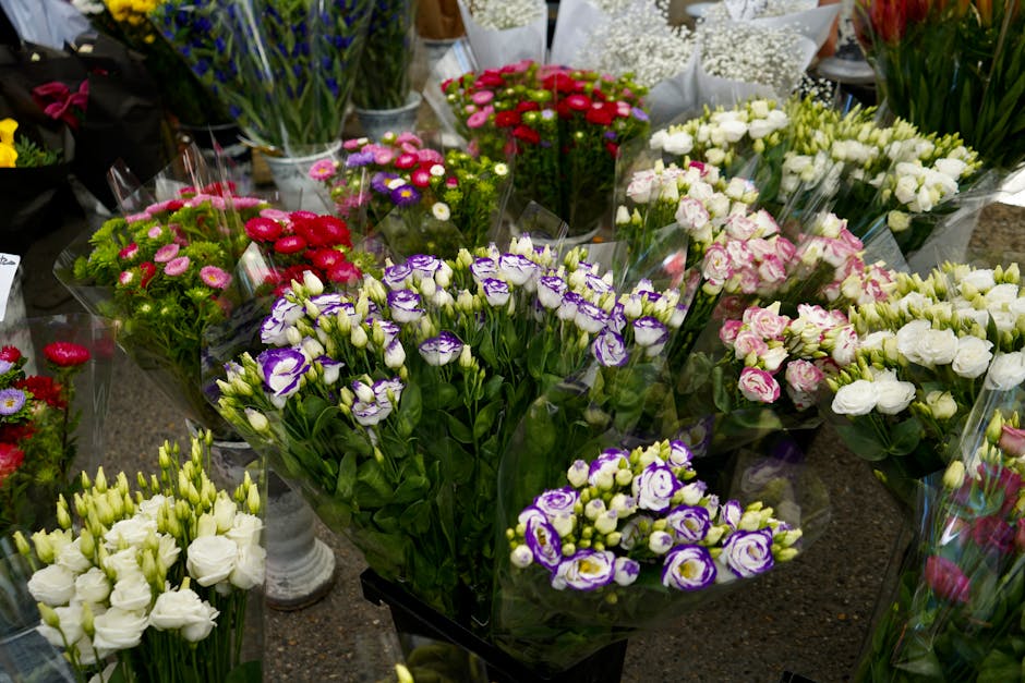 A display of fresh flower bouquets arranged on a dark surface inside a florist shop. The bouquets include a variety of flowers such as white lisianthus, purple and white eustoma (lisianthus), pink and